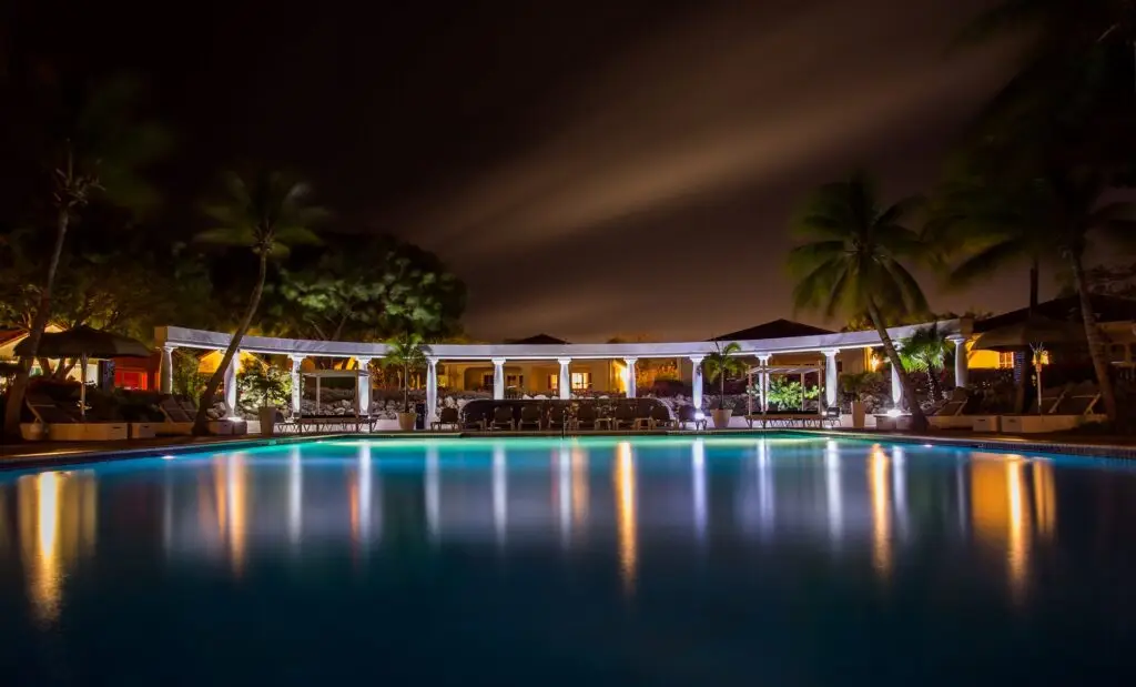 a pool with a building and palm trees at night