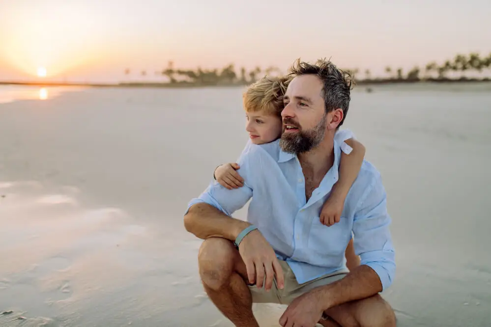 Father and child on beach at sunset.