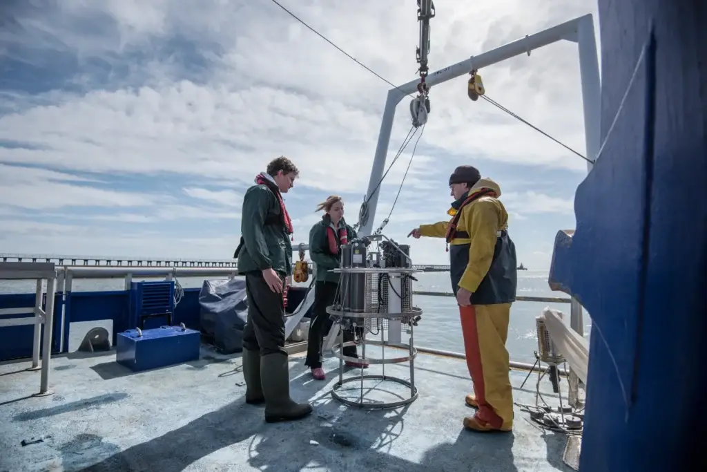 Scientists assembling sea-water sampling equipment on a research ship