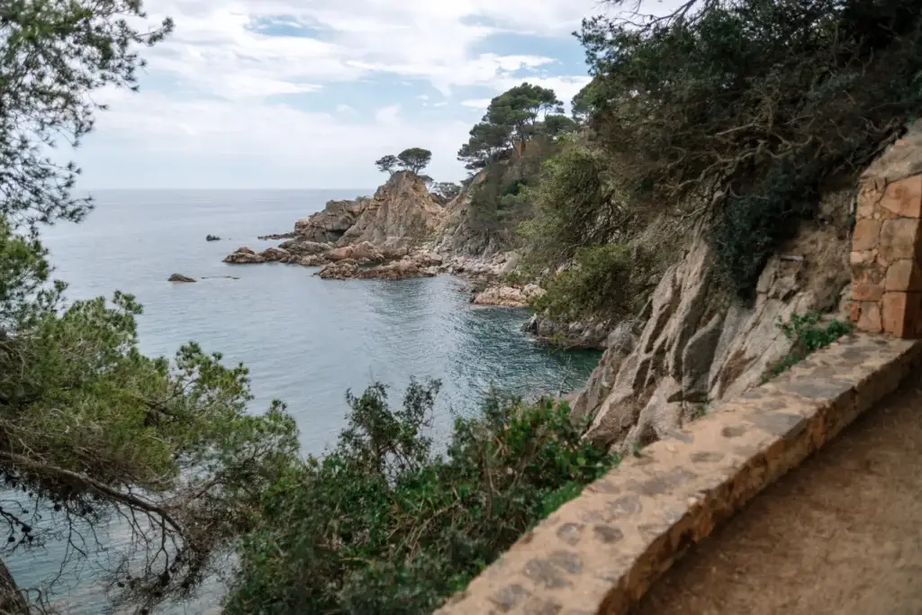 Stone coastal walkway descending toward the Mediterranean
