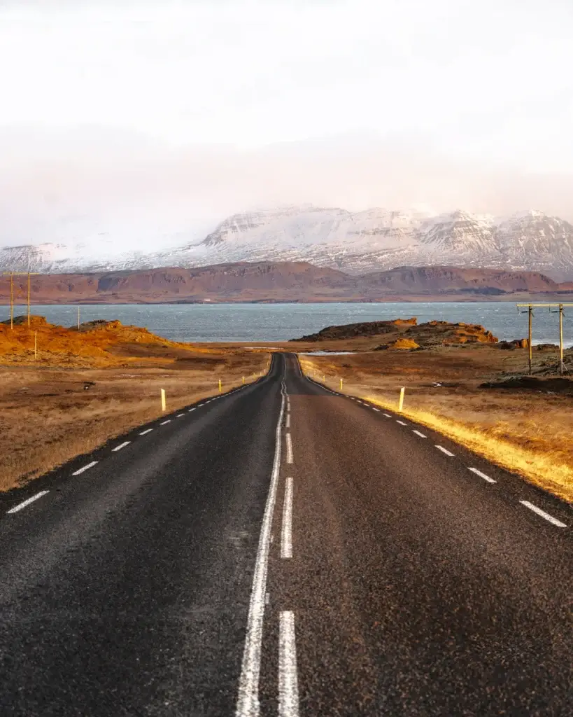 Ring Road crossing an open South Iceland landscape toward snow-covered mountains