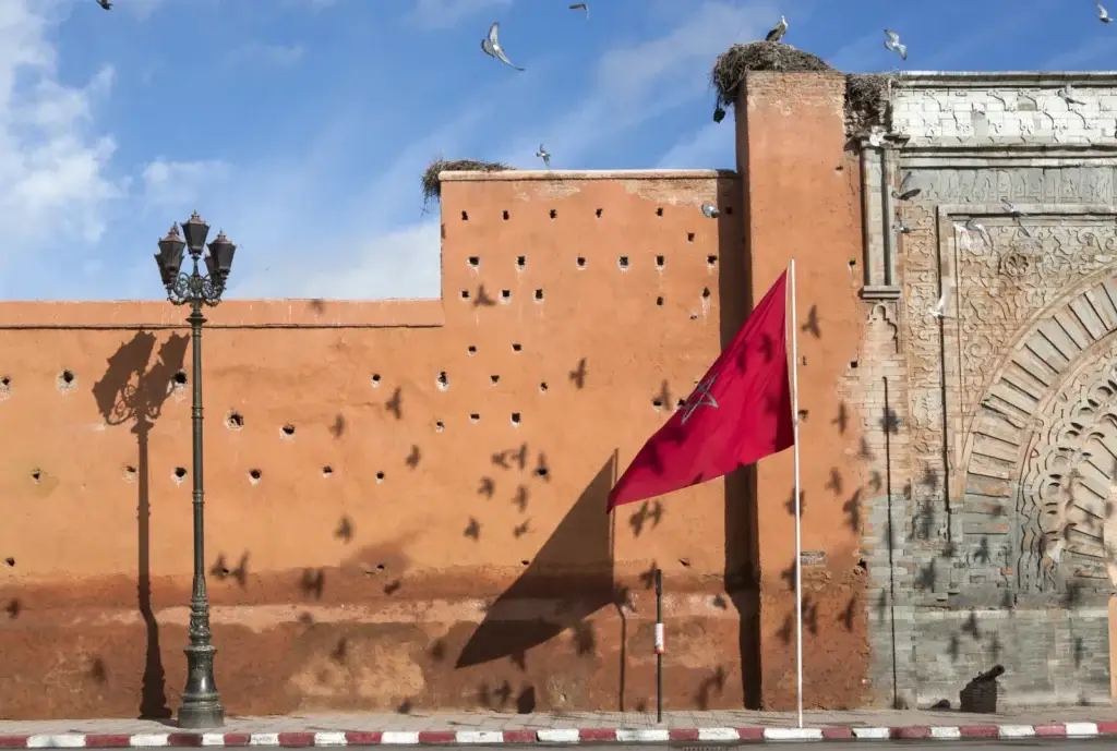 Moroccan flag beside an ornate gateway in Marrakech’s city wall