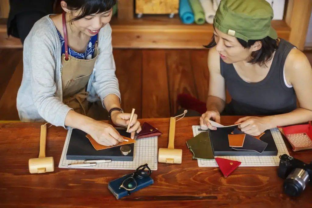 High angle view of two Japanese women sitting at a table, working in a leather shop.