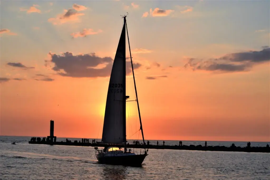 Sailboat Glides Past Pier at Scenic Sunset
