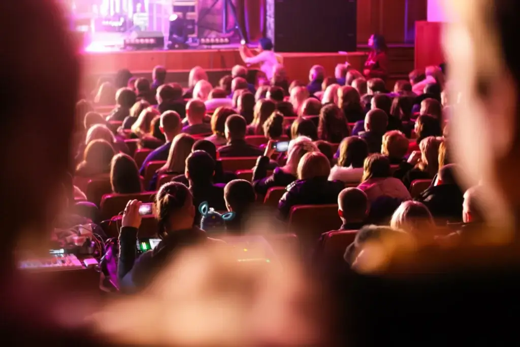 Spectators sit in the hall and watch a concert. People in the auditorium watching the performance. T