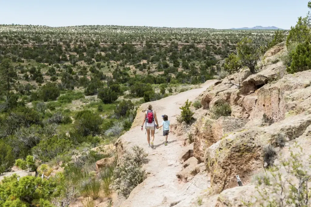 mother and her 5 year old son walking path, Tsankawi Ruins, NM