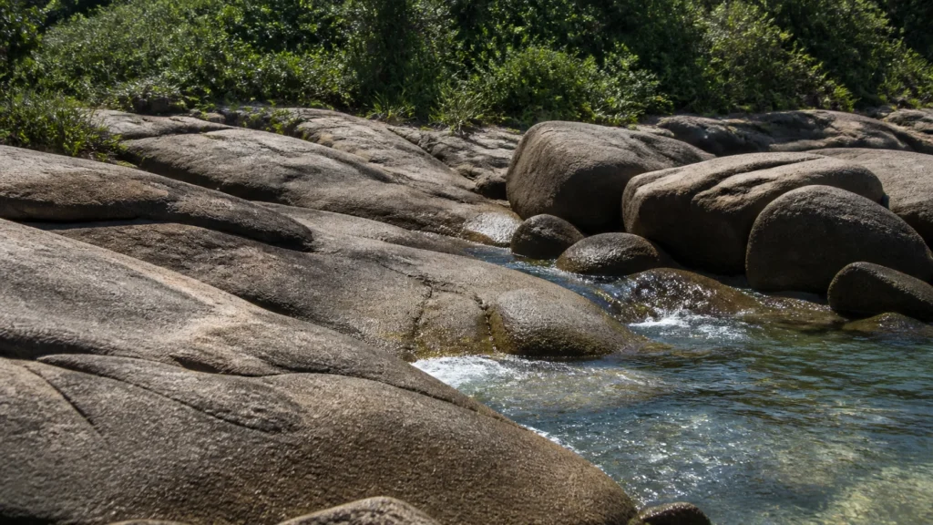 AI-generated editorial visualization of a granite-shore material context inspired by Ilha do Campeche, without archaeological depiction.