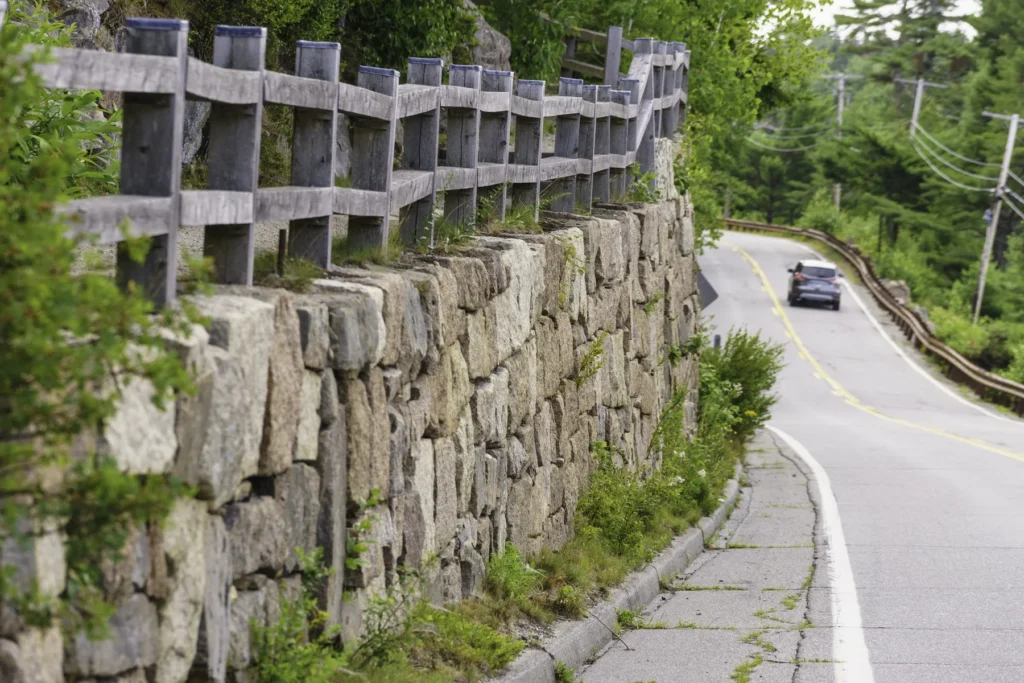 Long Stone Wall Topped By Wooden Fence Along A Winding Road On Mount Desert Island, Maine, Usa, In