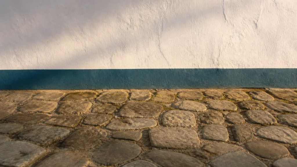 AI-generated editorial visualization of anonymous stone-paving and whitewashed-masonry material context inspired by Paraty.