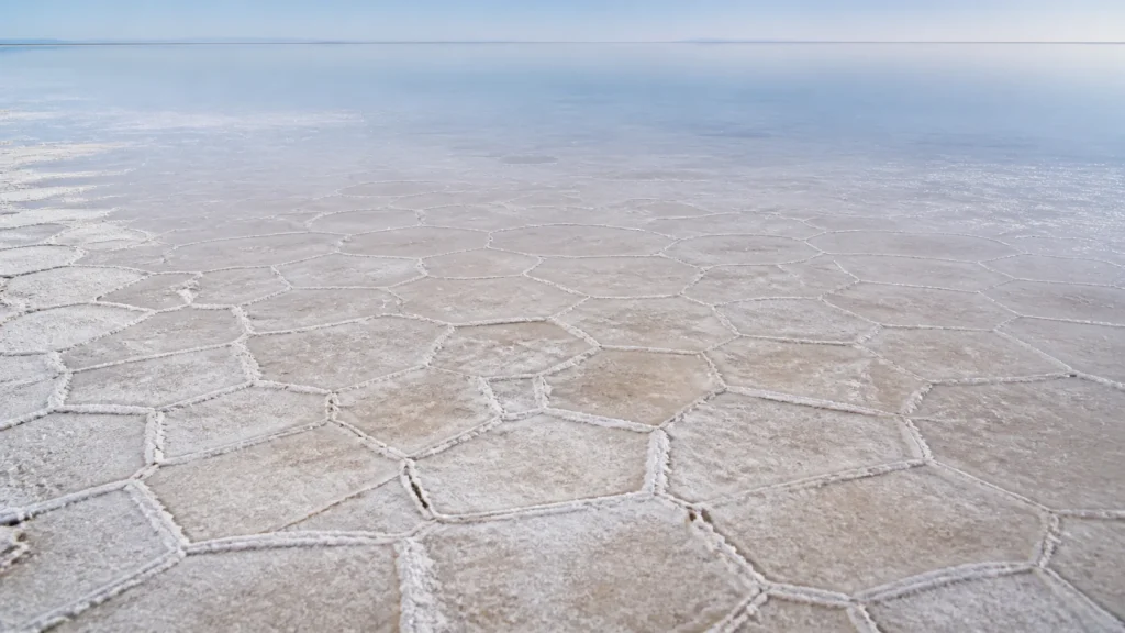 AI-generated editorial visualization of Salar de Uyuni salt-polygon and shallow-water processes; surface condition is illustrative, not current evidence.