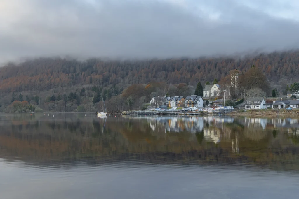 Kenmore reflected in Loch Tay, Perthshire, with autumn trees.