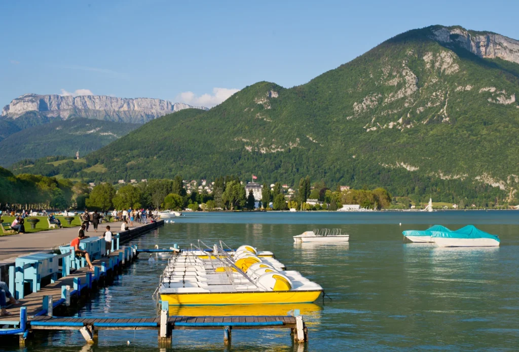 Small leisure boats on Lake Annecy, providing lake context. A scheduled cruise is not pictured.