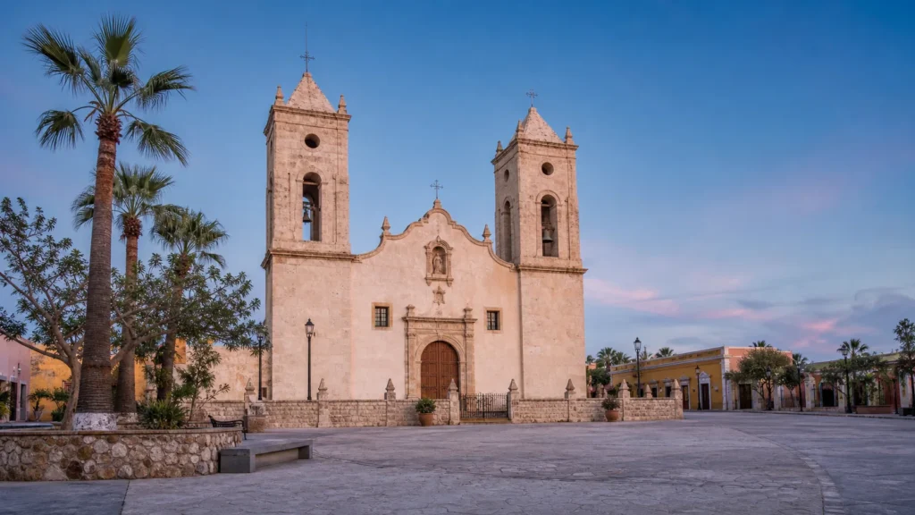 AI-generated editorial visualization of the public Plaza Mijares relationship to the documented twin-tower exterior of Mission San Jose del Cabo; not an exact current facade-artwork, illumination, event, access or condition record.