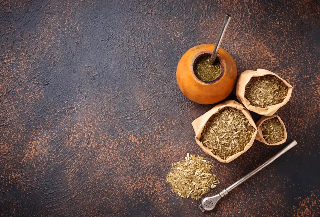 Yerba mate leaves with a gourd and bombilla.