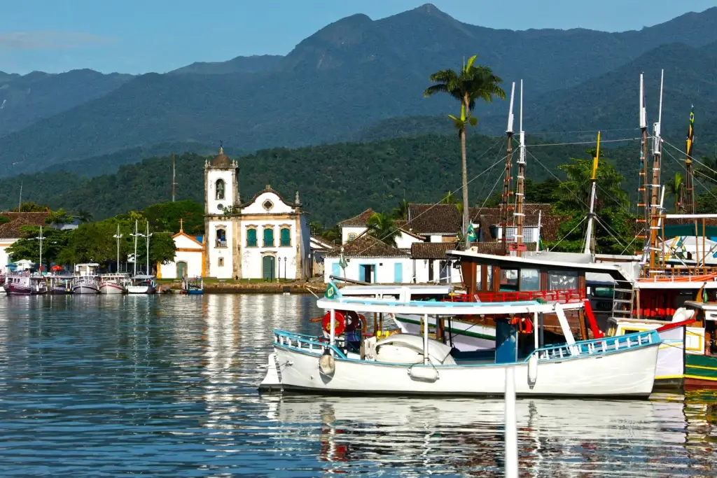 Boats on Paraty’s waterfront, with the historic town and forested mountains behind.